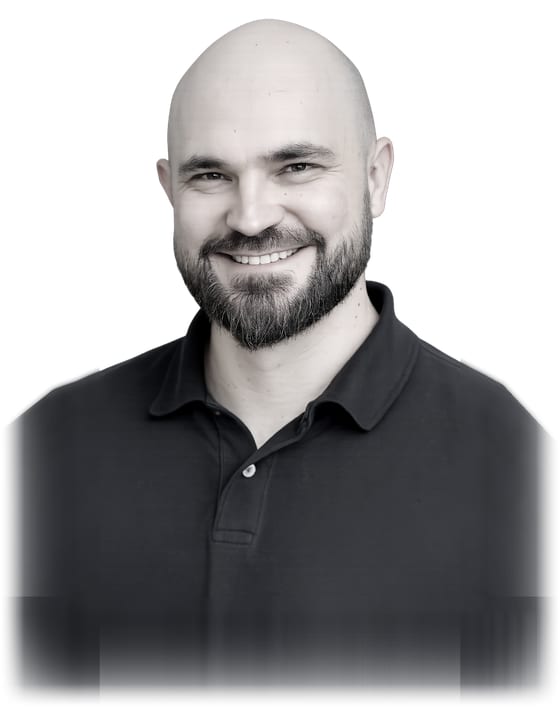 Marcio Prado in a black-and-white portrait, lit against a dark background